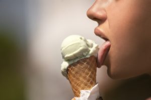 A person licking an vanilla ice cream cone